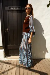 Falda midi de tul con estampado a rayas verticales en tonos marrón y blanco. Tiene volados verticales y cintura elastizada.