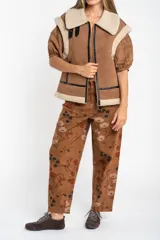 Chaleco estilo gamulán de color negro, con interior y cuello de corderito sintético. Presenta cierre frontal, detalles en cuero sintético y corte oversize.