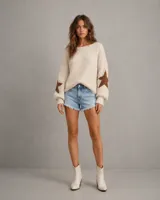 Sweater de punto grueso color crema, con diseño de estrellas marrones en las mangas, cuello redondo y mangas largas con puños ajustados.