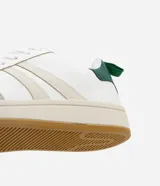 Championes de estilo casual, color blanco, con detalles en beige claro en los laterales y puntera de gamuza color gris claro. Posee suela de goma color caramelo y tirador trasero en color verde oscuro.