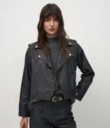 Campera estilo biker confeccionada en denim oscuro, con diseño estructurado, cuello con solapas, cierre frontal asimétrico y botones a presión metálicos.