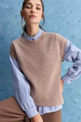 Chaleco de tejido de punto color beige claro, con cuello redondo y diseño de líneas limpias con hombros caídos y terminaciones acanaladas.