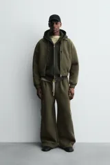 Cazadora de corte boxy fit confeccionada en tejido técnico compacto de algodón con elasticidad. Presenta cuello solapa, cierre frontal con cremallera, bolsillos de vivo en la cadera y acabados elásticos en puños y bajo.