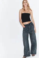 Jeans de tiro medio con corte baggy y cinco bolsillos. Presenta un diseño de estampado floral realizado con aplicaciones de strass a contraste sobre el tejido denim.