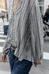 Blusa de manga larga con cuello redondo y escote en pico, cierre frontal con botones y diseño de rayas verticales.