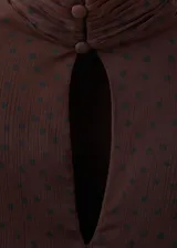 Vestido corto marrón con estampado de lunares, cuello alto y diseño de capas superpuestas con volados. Mangas largas abullonadas semitransparentes.