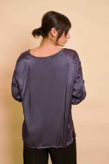 Blusa holgada de satén color beige, con escote en V y mangas largas con trabilla para sujetar remangadas.