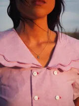 Blusa blanca de lino, de manga corta, con cuello marinero amplio decorado con estampado azul.