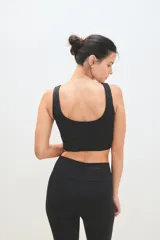 Top deportivo de escote redondo y espalda estilo nadador, confeccionado en tejido técnico elástico. Presenta un diseño ajustado al cuerpo con pretina ancha para mayor soporte.