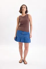 Falda corta de jean color azul medio, de tiro medio con diseño de volado en el ruedo.