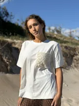 Remerón de algodón blanco, corte holgado y manga corta, con un bolsillo frontal de crochet color beige.