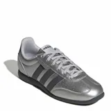 Championes urbanos Adidas modelo Barreda Lo, color plateado metalizado con las icónicas tres tiras en color negro y suela oscura. Presentan un diseño de perfil bajo con perforaciones en la puntera y cordones al tono.