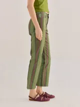 Pantalón de tiro medio con diseño de rayas verticales en tonos marrones, naranjas y amarillos, de corte recto y holgado.
