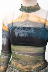 Remera crop top de mangas largas y cuello alto, confeccionada en tejido de red transparente con estampado de paisaje montañoso.