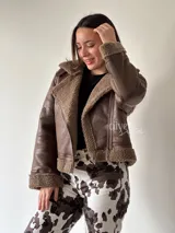 Campera marrón de cuero sintético con interior de piel sintética color beige, cierre cruzado con cremallera y hebilla en el cuello.