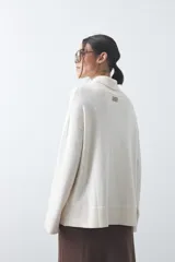 Polera de tejido liviano color negro con cuello alto y silueta relajada. Presenta mangas largas con puños ajustados y recortes laterales que aportan estructura al diseño.