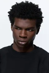 Buzo negro de tejido liviano con mezcla de algodón y viscosa, manga raglán y cuello redondo. Puños y bajo acanalados. Corte oversized para una silueta holgada.