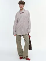 Camisa oversize de popelina de algodón con diseño de rayas verticales, cuello clásico, cierre frontal con botones, manga larga con puños anchos y bolsillo aplicado en el pecho.