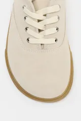 Zapatillas tipo deportiva confeccionadas en serraje color beige, con diseño barefoot de puntera amplia, suela flexible efecto engomado y cierre mediante cordones al tono.