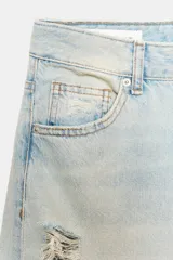Jeans baggy de tiro medio, color azul claro con efecto lavado y rotos en las piernas. Cuenta con cinco bolsillos y cierre frontal de cremallera y botón metálico.