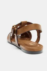 Sandalias estilo cangrejera plana de color marrón, con diseño de tiras entrelazadas en la parte delantera y cierre ajustable mediante hebilla metálica en el tobillo.