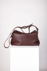 Cartera negra de cuero granulado, con cierre metálico y doble correa regulable y desmontable. Cuenta con un bolsillo interior con cierre y otro para el celular.
