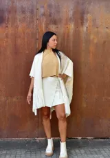 Ruana tejida de lana en color crudo, con diseño de flecos en los bordes. Es una prenda versátil y abrigada, ideal para complementar diversos looks.