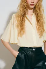 Blusa oversize en mezcla de algodón y viscosa, color amarillo claro, con cuello mao, botonadura frontal y mangas cortas abullonadas con terminación en broderie.