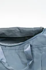 Bolso de viaje gris con doble asa corta y cierre superior. Estampado frontal con la frase "The Tote Bag" en letras blancas.