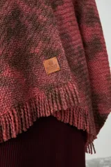 Ruana de tejido de punto con diseño teñido artesanalmente en tonos coral y marrón, con terminación de flecos en el ruedo.