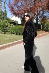 Conjunto de dos piezas confeccionado en tejido plush aterciopelado color negro. Incluye un buzo de corte cropped con cuello redondo y mangas largas, y un pantalón estilo cargo de silueta holgada con bolsillos laterales funcionales y puños ajustables en los tobillos.
