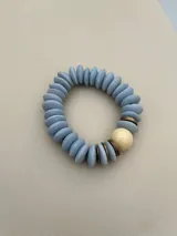 Set de tres pulseras elásticas con cuentas de madera en colores celeste, negro y rosa, con detalles de cuentas doradas y cuentas color crema.