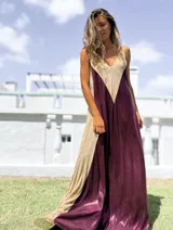 Vestido largo de corte holgado con diseño bicolor en tonos bordó y dorado, confeccionado en tela satinada con acabado brillante. Presenta escote en V y breteles anchos.