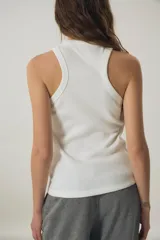 Musculosa de morley color blanco, con escote estilo halter y detalle de texto bordado en negro en el pecho.
