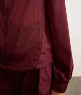 Campera rompevientos deportiva de mujer, marca Get Over, color beige con sutiles rayas verticales, cuello alto, cierre frontal con cremallera y puños ajustados.