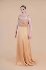 Vestido largo de fiesta color oro, confeccionado en gasa de seda natural con corsé drapeado, mangas y faja en tul bordado.