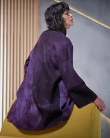 Tapado de lana merino afieltrada color violeta con teñido artesanal Tie Dye en forma de luna. Tiene cierre cruzado asimétrico con broches, cuello alto y bolsillos laterales.