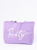 Bolso tipo tote de tela ligera color lila, con doble asa de hombro y estampado frontal con el logo de la marca Rusty en color blanco.