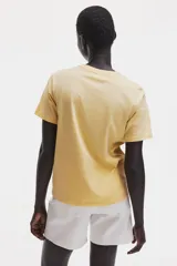 Remera de corte recto en punto suave de algodón, color amarillo, con cuello redondo ribeteado y hombros ligeramente caídos.
