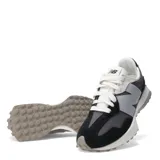 Championes New Balance modelo 327, con capellada en tonos negro, gris oscuro y gris claro. Presenta el logo 'N' sobredimensionado en gris claro y cordones blancos. La suela es gruesa, de color blanco con detalles en goma gris/tostada en la punta y el talón.