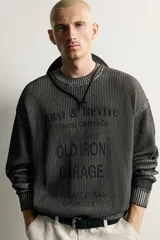 Sweater relaxed fit de algodón color gris con efecto lavado, cuello redondo, manga larga y diseño de textos estampados a contraste en el frente.