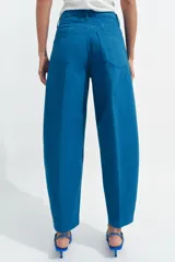 Jeans de tiro alto con corte tapered y largo al tobillo. Presenta cinco bolsillos, trabillas en la cintura, cierre frontal con cremallera y botón, y detalle de raya planchada en el frente.