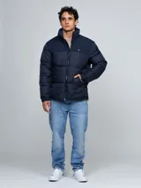 Campera puffer azul marino de cuello alto, acolchada y con cierre frontal de cremallera. Presenta bolsillos laterales con ojal y el logo bordado de la marca en el pecho.