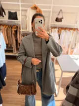 Cartera tipo baguette con estampado animal print, confeccionada en material suave símil gamuza. Presenta un bolsillo frontal con solapa y cierre, compartimento principal con cierre superior, y asa larga regulable de cuero sintético marrón.