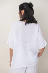 Blusa de lino color blanco, de corte amplio, con escote redondo, mangas cortas y detalle de guarda calada horizontal en la parte inferior.