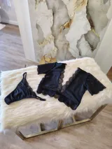 Conjunto de lencería compuesto por un top bralette y una tanga. El top presenta un diseño con escote profundo, mangas cortas de encaje y detalles de encaje en los bordes. La tanga es de corte regulable, confeccionada en lycra y encaje con forro de algodón.