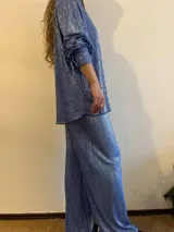 Camisa plisada color celeste con brillo, de corte holgado y manga larga con puños elásticos.
