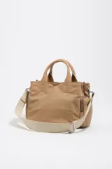 Bolso bandolera Pocket Bimba Y Lola de tamaño mediano, color tostado, confeccionado en nylon con estructura blanda, doble asa de mano y correa de tejido. Incluye un bolsillo exterior frontal con cierre y el logo metálico de la marca.