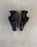 Zapatillas urbanas de cuero vacuno color negro, con suela alta y cordones.