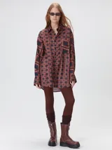 Camisa de seda con estampado geométrico de cuadrados en tonos rojizos y marrones. Presenta cuello camisero, cierre frontal con botones, bolsillo en el pecho y mangas largas con puños abotonados.